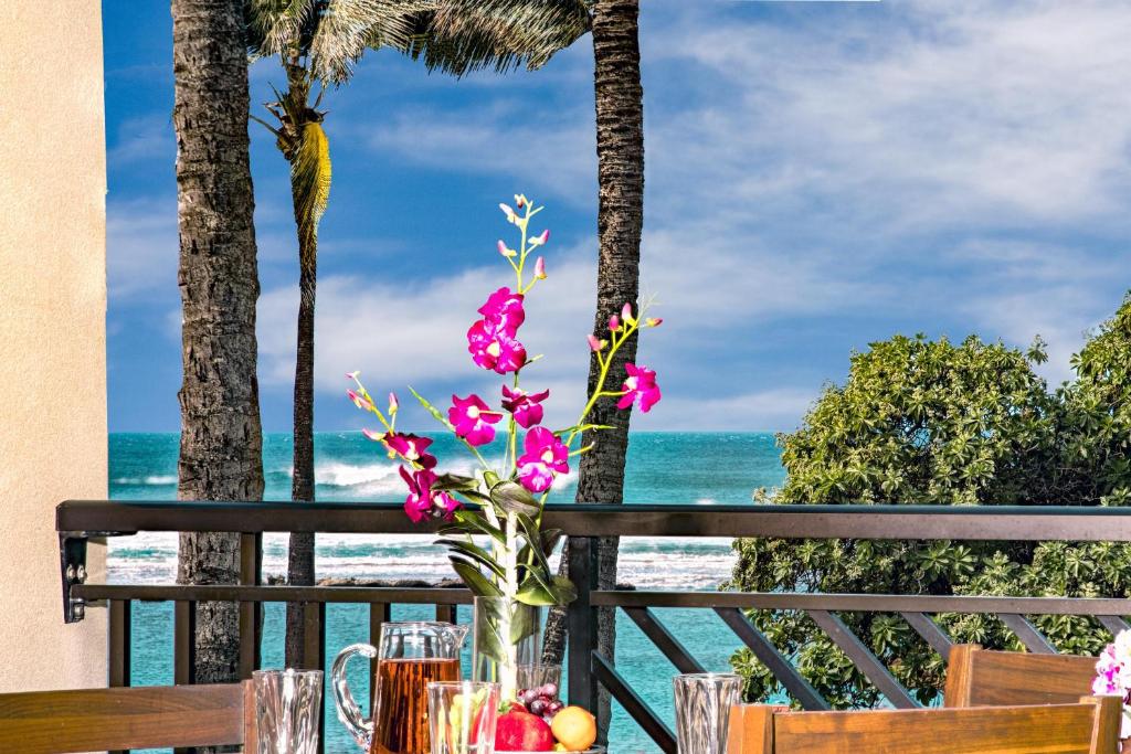 a table with flowers and the ocean in the background at Villa 202 at Turtle Bay in Kahuku