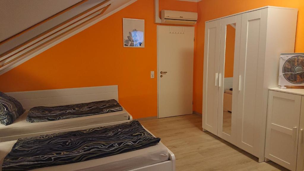 a room with two beds and an orange wall at Dreibettzimmer mit Gemeinschaftsküche und je 2 Dusch- und 2 Toilettenzimmern in Hohenstein-Ernstthal