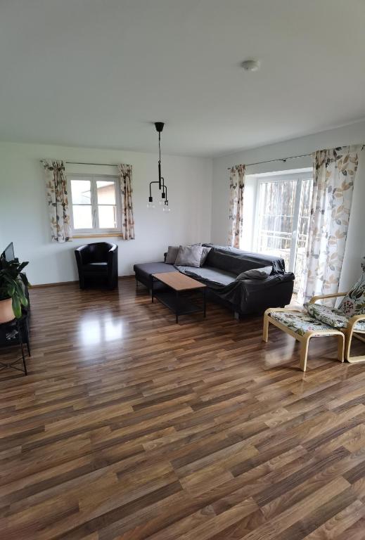 a living room with a black couch and wooden floors at Niedergerner Alpaka Ranch Groß in Kemerting