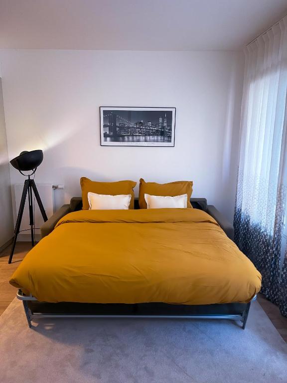 une chambre avec un lit avec une couverture jaune dans l'établissement Grand appartement, à Clichy