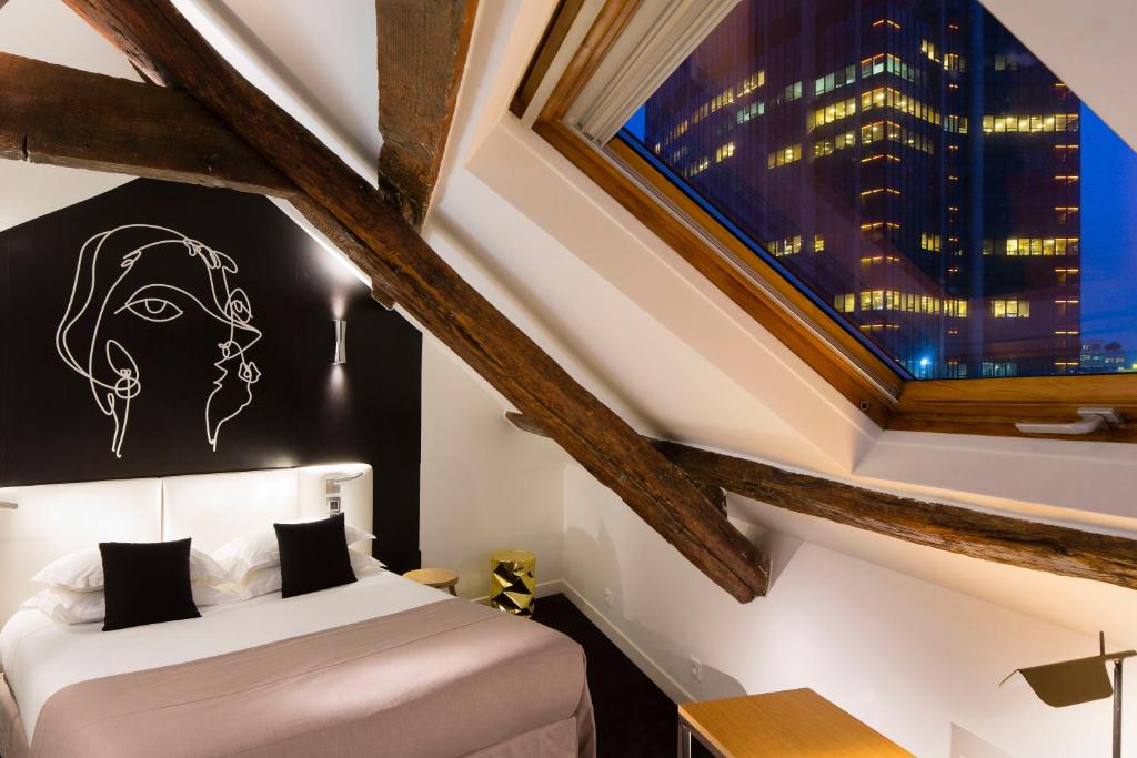 um quarto com uma cama e uma grande janela em Hôtel Montparnasse Saint Germain em Paris