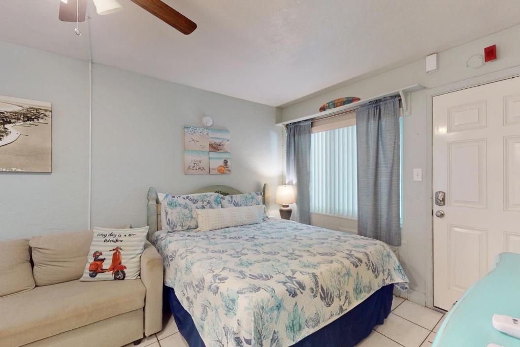 een slaapkamer met een bed en een bank bij Pass-A-Grille Beach Retreat Unit 8 in St Pete Beach