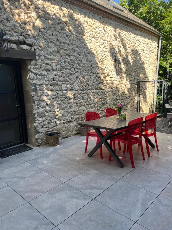 a picnic table with red chairs and a stone wall at Maison au bord de la Loire in Saint-Jean-le-Blanc