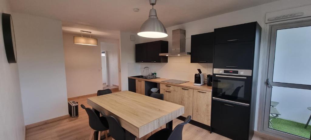 une cuisine avec une table en bois et des appareils noirs dans l'établissement Chambres avec salle d'eau privative dans appartement partagé, à Toulouse