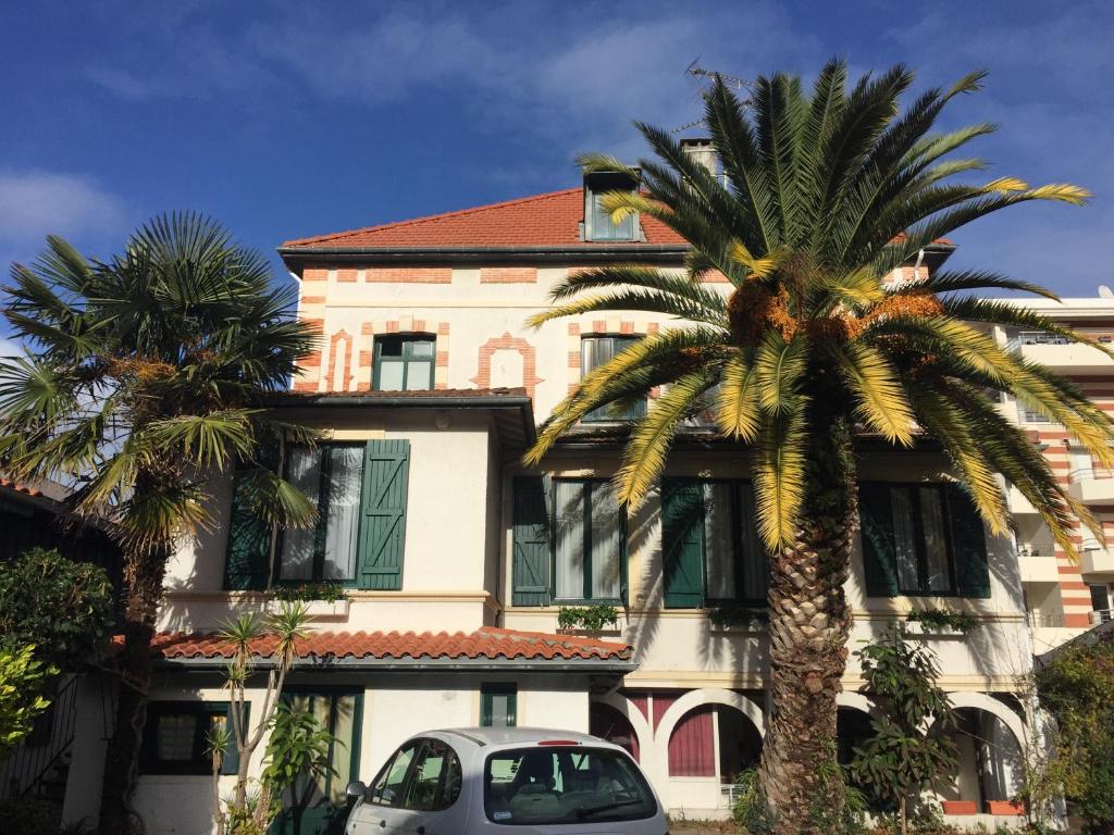 a palm tree in front of a building at Hôtel-Résidence Le Grillon in Arcachon