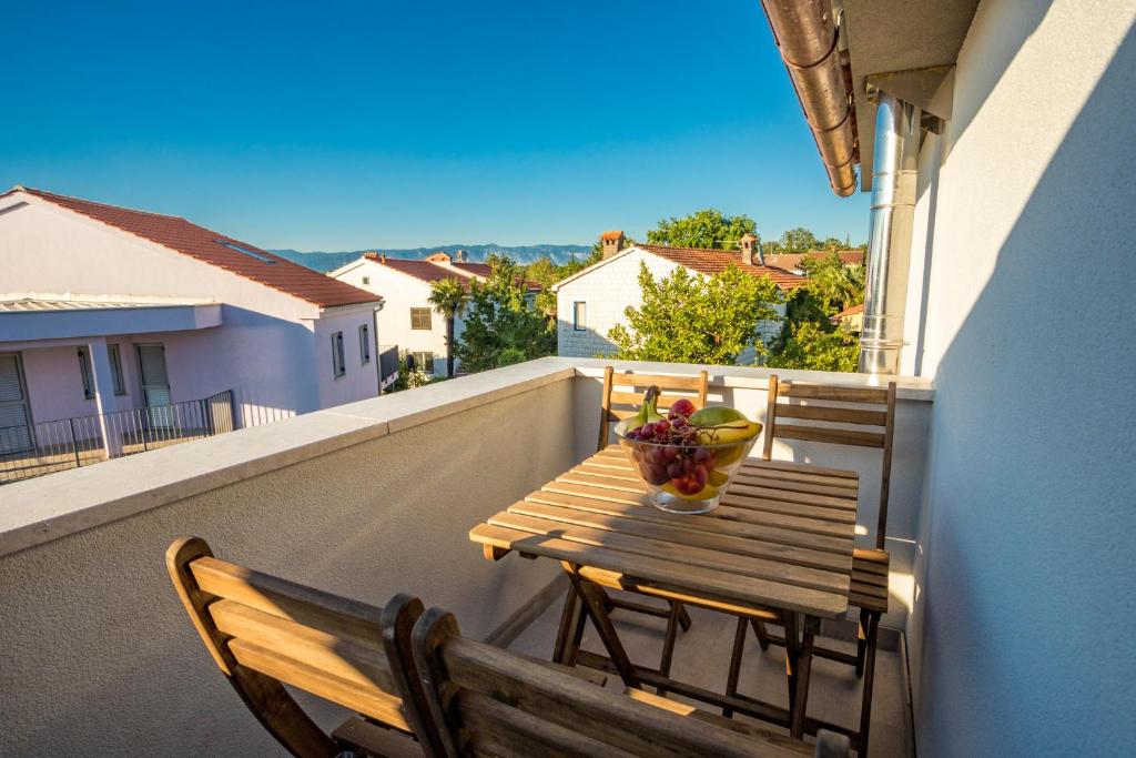 a wooden table and bench on a balcony with a bowl of fruit at Sunset Holiday3 in Njivice
