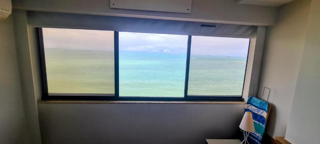 a view of the ocean from a window in a room at Flat Pasárgada 906 - Apt com vista frontal da Praia da Costa, academia moderna, piscinas panorâmicas, minimercado e lavanderia in Vila Velha
