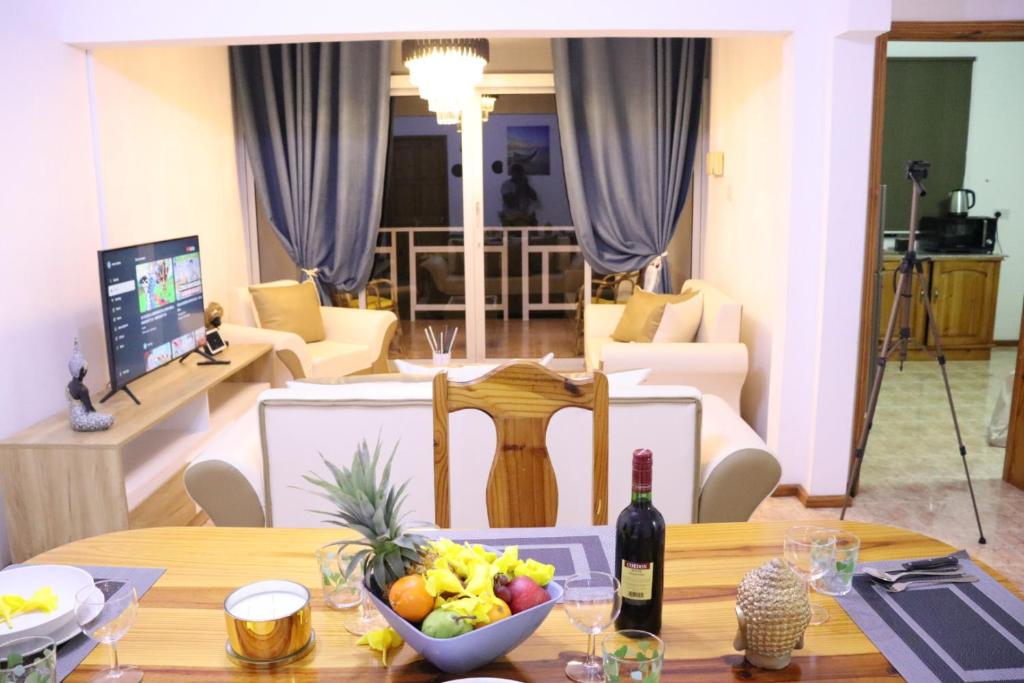 a table with a bowl of fruit and a bottle of wine at Family Luxurious Beach Penthouse in Trou d'Eau Douce