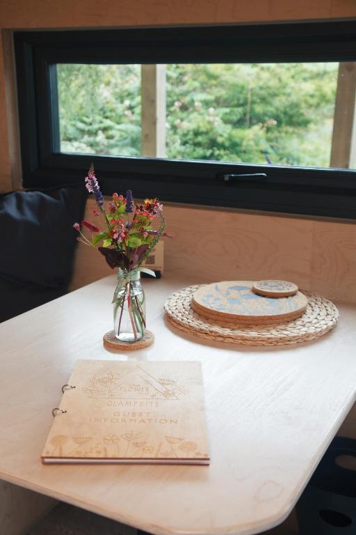 a table with a vase of flowers and a plate at Luxury Glamping Cabin with Outdoor Bath on Cornish Flower Farm in Truro