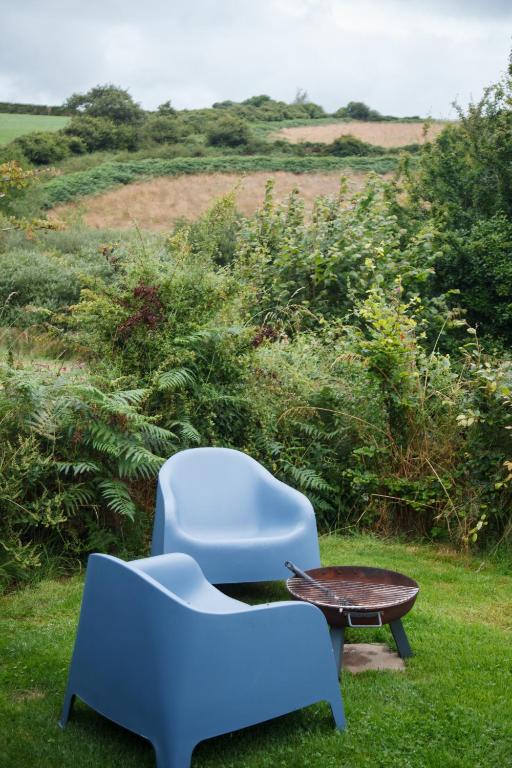 two blue chairs and a coffee table in the grass at Luxury Glamping Cabin with Outdoor Bath on Cornish Flower Farm in Truro