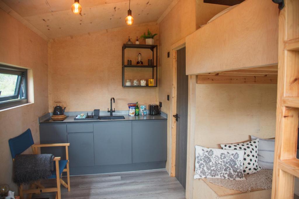 a tiny house with a kitchen and a loft bed at Luxury Glamping Cabin with Outdoor Bath on Cornish Flower Farm in Truro