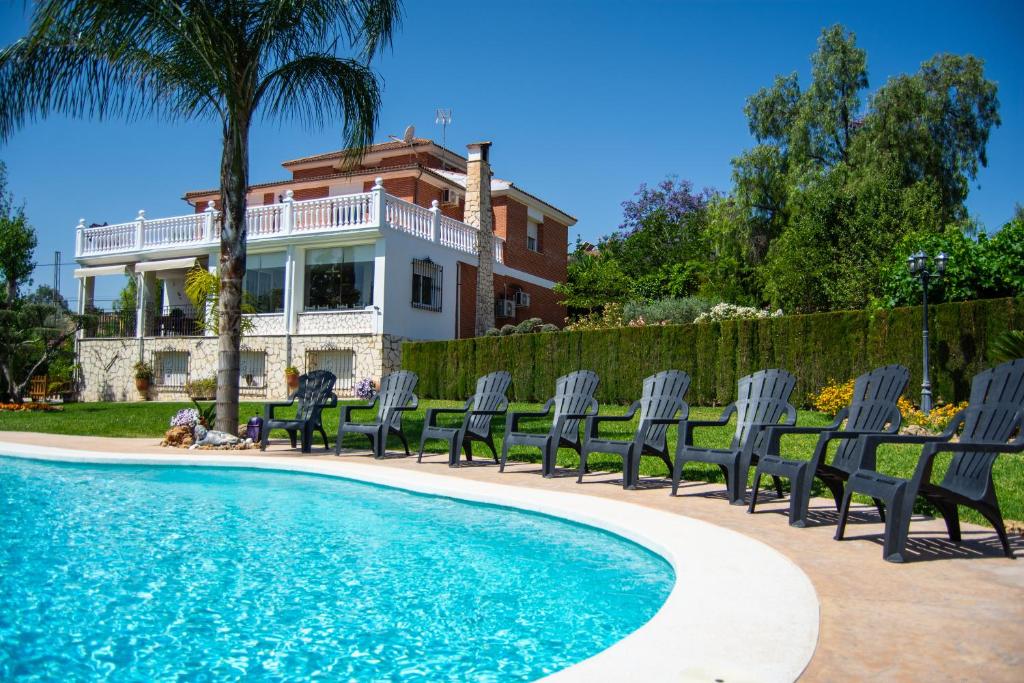 Una piscina con sillas y una casa al fondo. en Alojamiento Rural Las Acacias, en Cabra