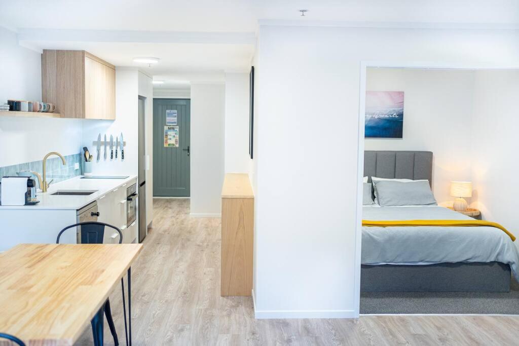 een keuken en een slaapkamer met een bed in een kamer bij The Downtown - A Mount Maunganui Apartment in Mount Maunganui