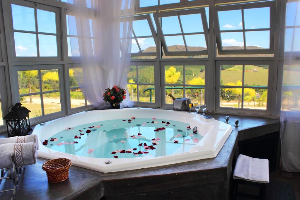 a jacuzzi tub in a large room with windows at Varandas da Montanha in Carmo do Rio Claro