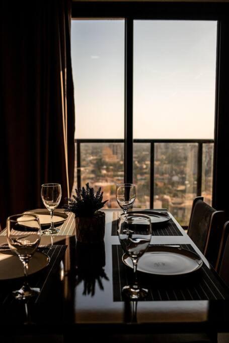 a table with wine glasses on it with a large window at Loft Aconchegante Centro in Dourados