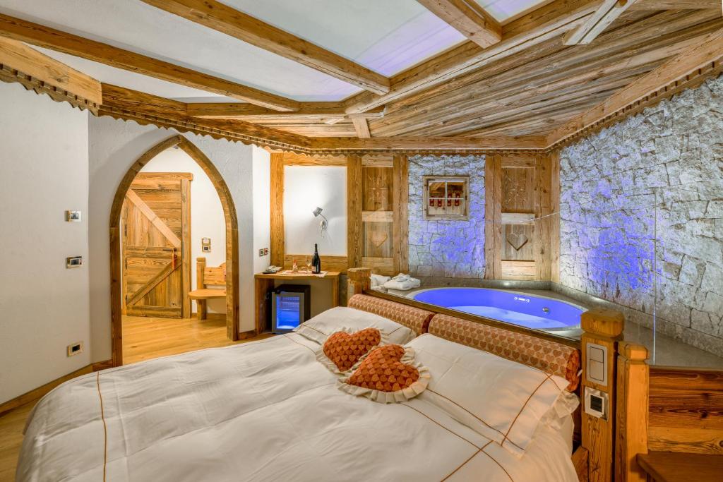 a bedroom with a large bed and a tub at Chalet Pineta relax location in Canazei