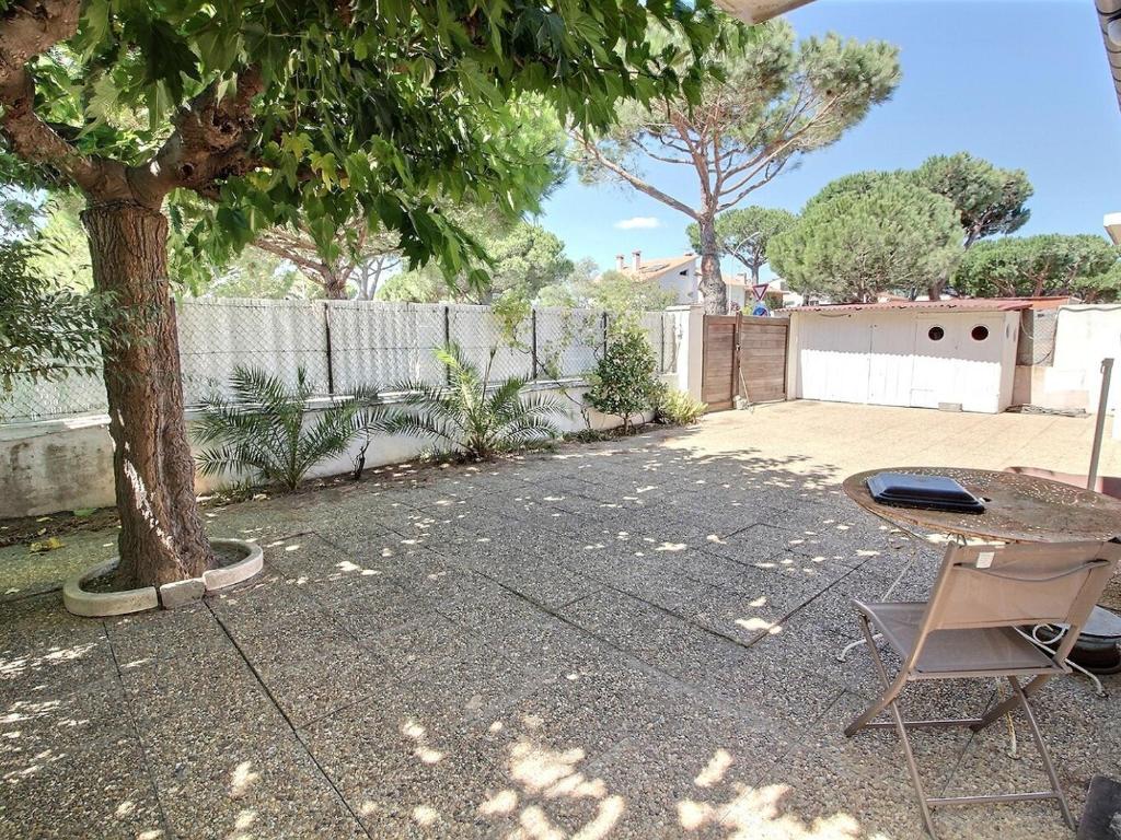 d'une terrasse avec une table et un arbre. dans l'établissement Charmante maison à Canet, proche commerces et parcs - FR-1-732-89, à Canet