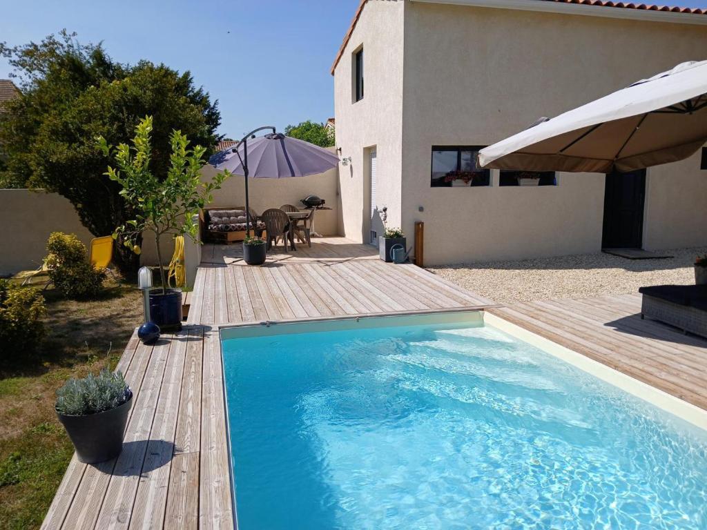 a swimming pool with a wooden deck and a house at Gîte avec piscine chauffée, jardin clos et WiFi à Baignes - FR-1-653-264 in Baignes-Sainte-Radegonde