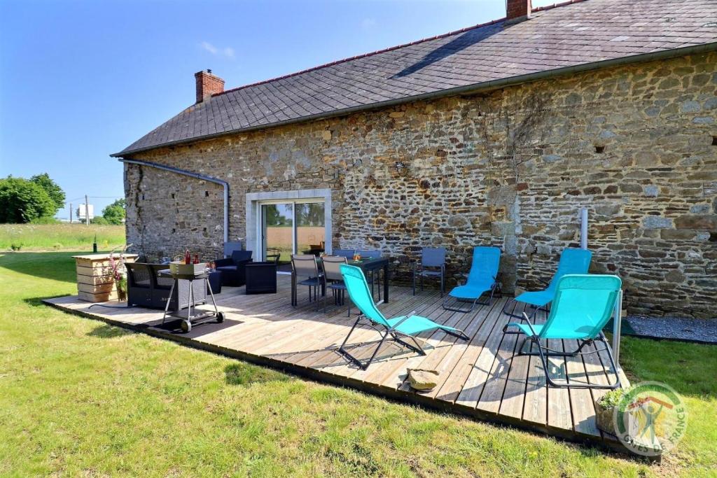 a deck with chairs and tables in front of a brick building at Breizh roch in Maen Roch