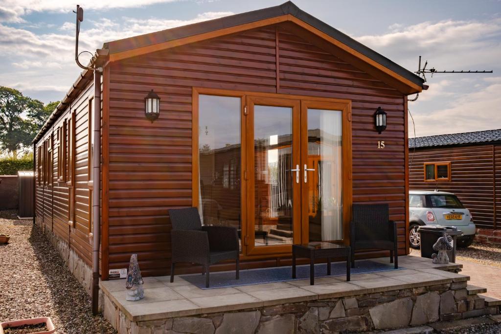 a wooden cabin with two chairs and a table at Luxury Lodge in Forfar