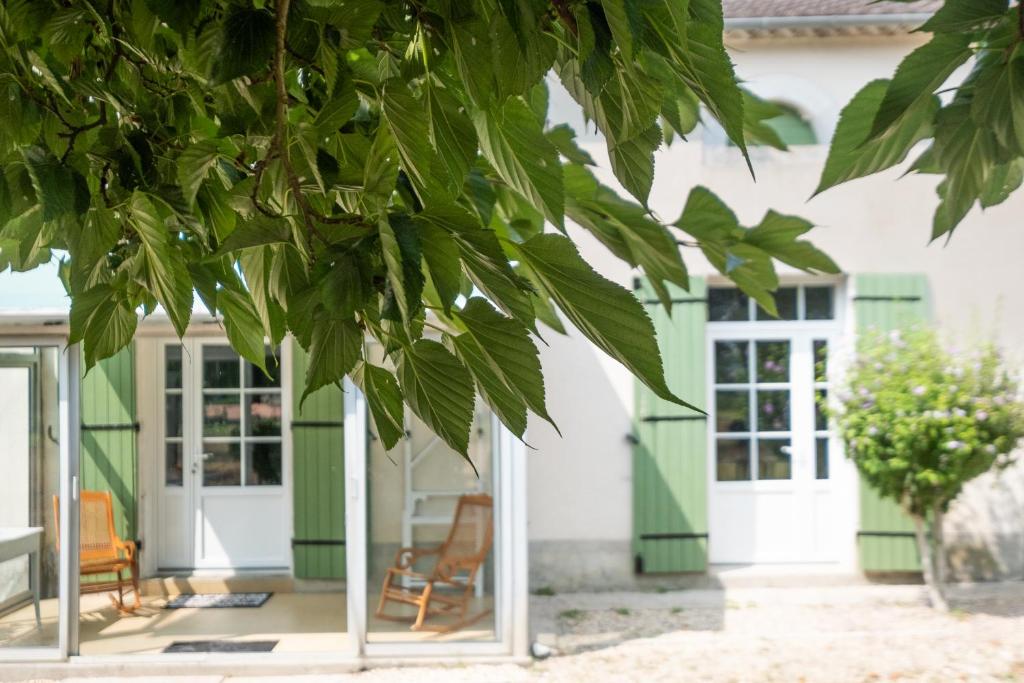 une maison avec des portes vertes et blanches et un arbre dans l'établissement Gite du Sourcier, à Sadillac