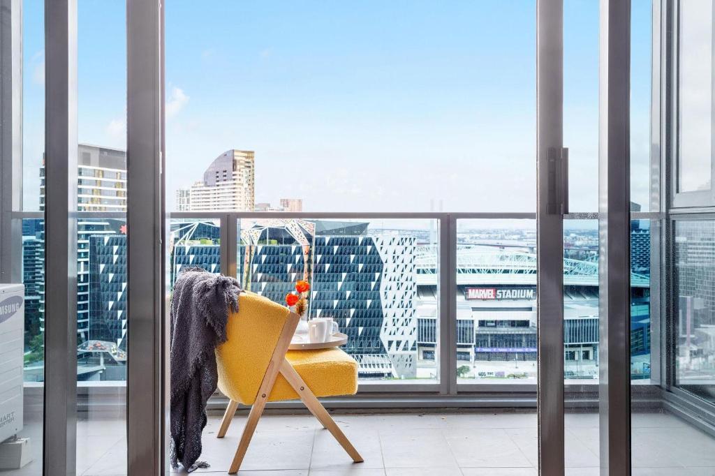 a yellow chair in a room with a window at A 2BR Apt with Harbour Views and FREE Parking in Melbourne