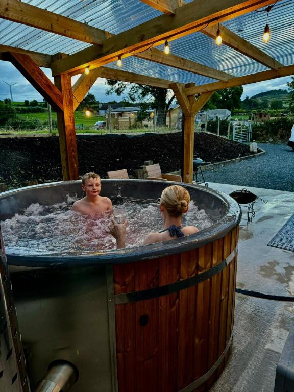 two people in a hot tub in a backyard at Dundrine Cottage in Maghera