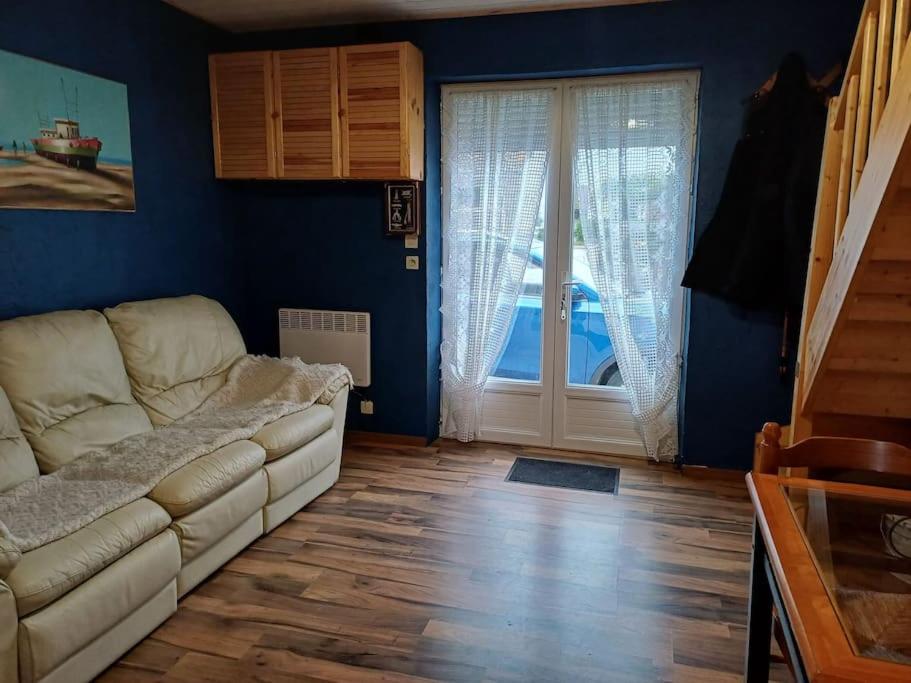 un salon avec un canapé et une porte coulissante en verre dans l'établissement Maison avec terrasse Merlimont Plage, à Merlimont