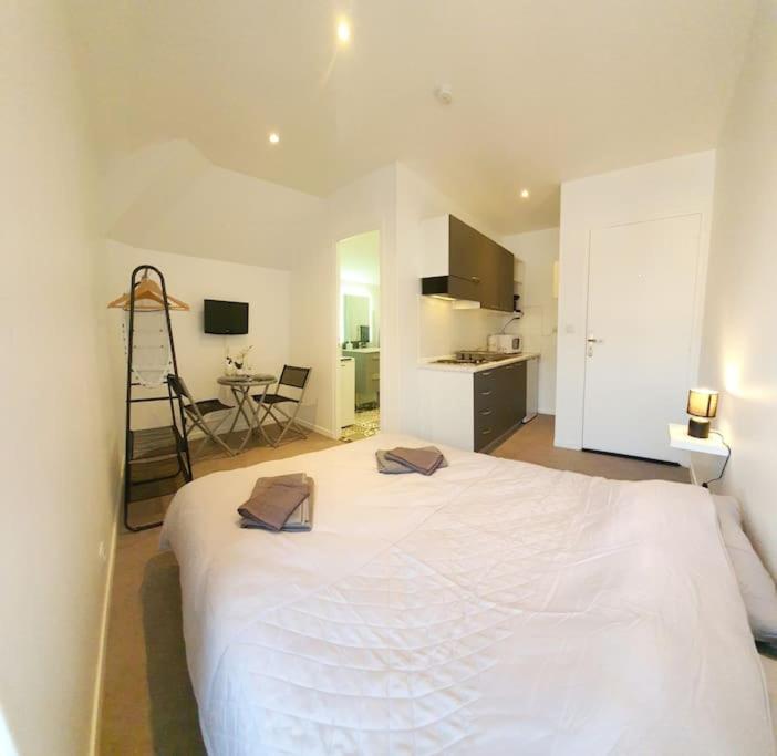 een groot wit bed in een kamer met een keuken bij Chic & Contemporain in Vierzon