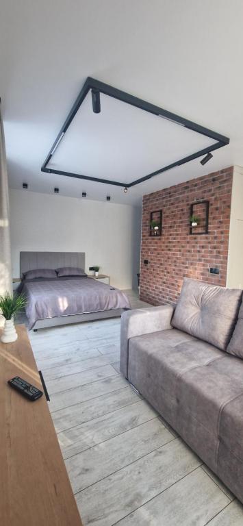 ein Wohnzimmer mit einer Couch und einer Ziegelwand in der Unterkunft Апартаменты на Чехова in Öskemen