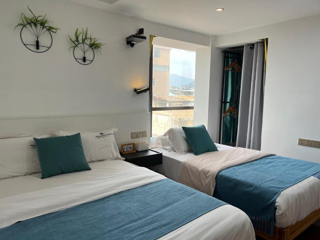 two beds in a room with a window at 桂林依庐居民宿 in Guilin