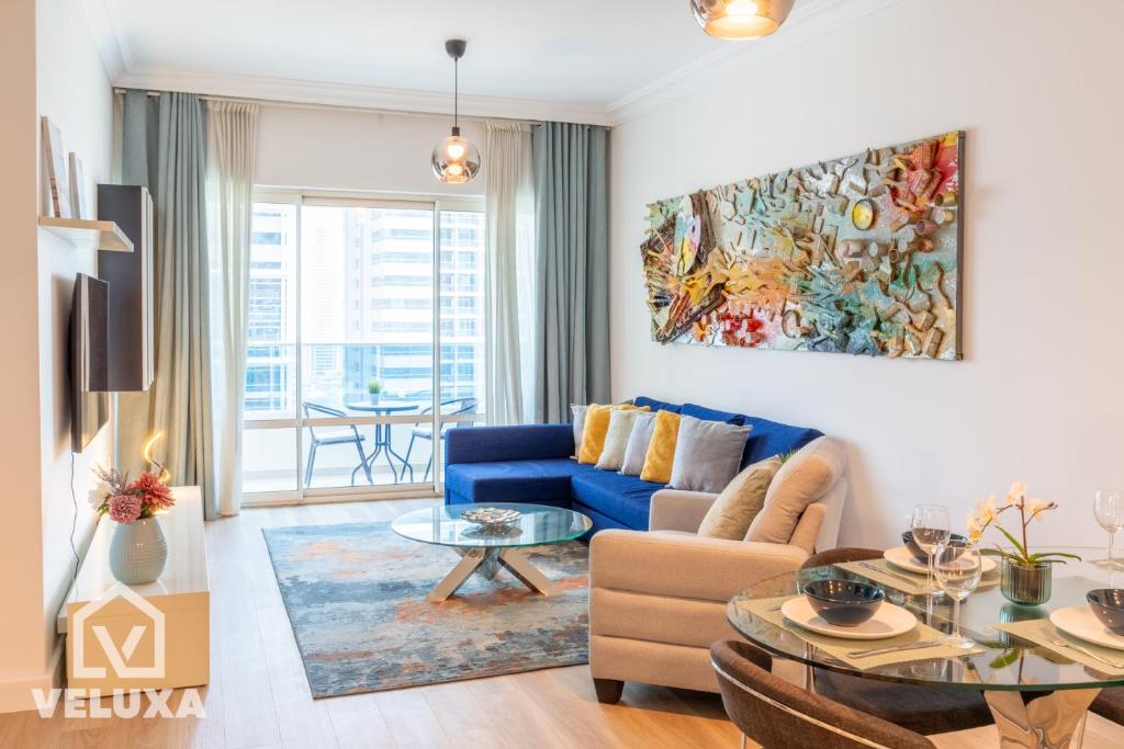 a living room with a blue couch and a table at Veluxa - Renovated! La Maison des Artist in Dubai