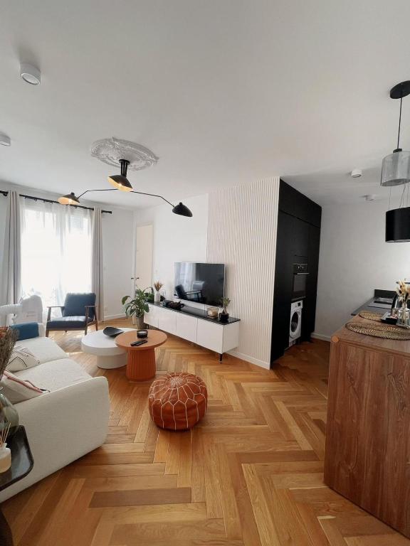 un salon avec un canapé blanc et une télévision dans l'établissement Exclusive Flat By Luxuio - Nearby Eiffel Tower, à Paris