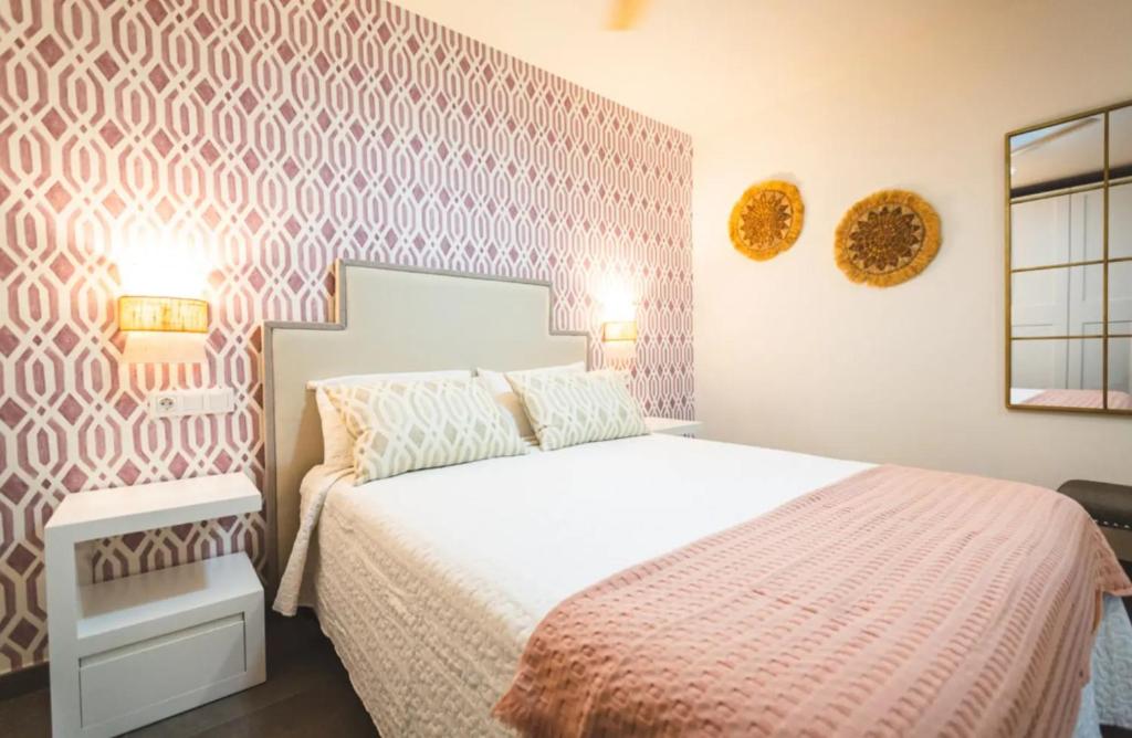 a bedroom with a white bed with a pink patterned wall at Flores de Cordoba Gitanilla 2 in Córdoba