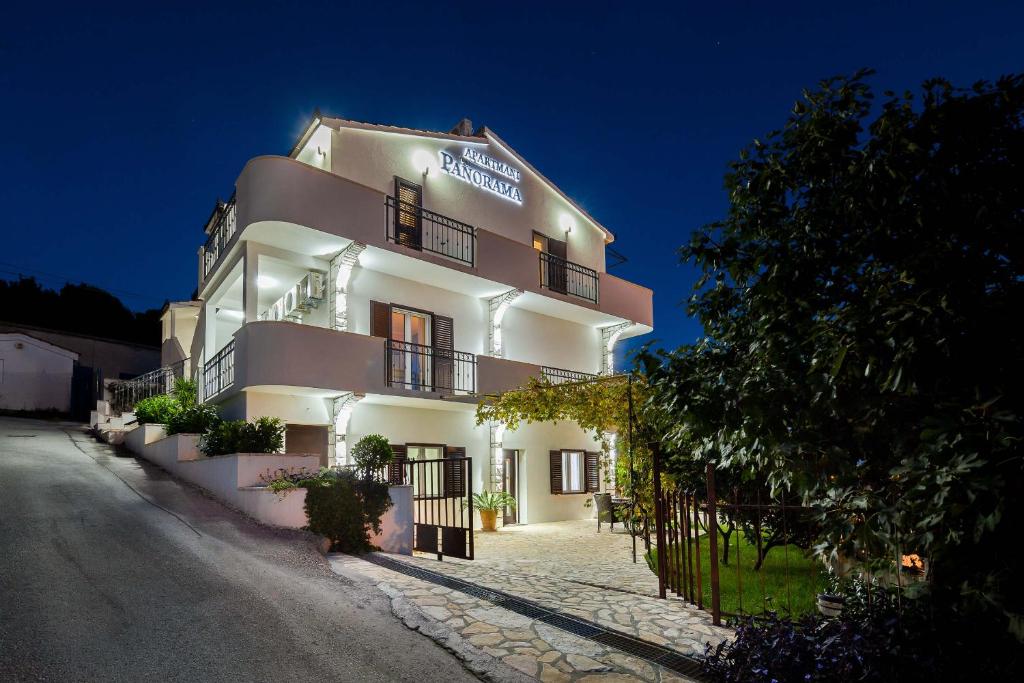een wit gebouw met 's nachts een bord bij Apartments Panorama in Trogir