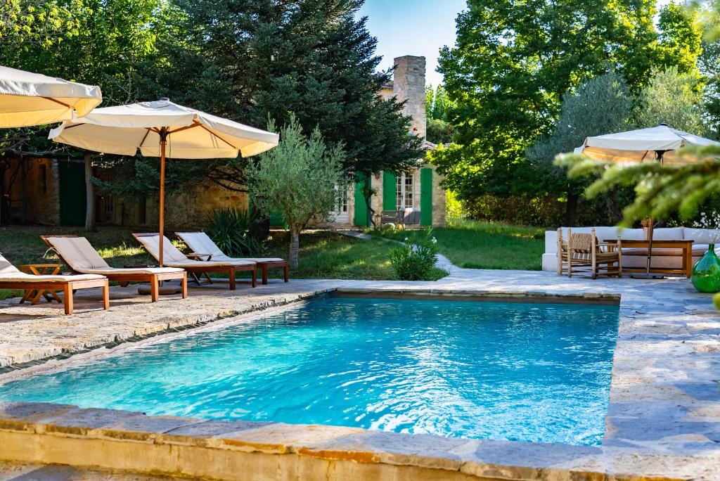 une piscine avec des chaises et un parasol dans l'établissement Collection Sojourn - Le Mas, à Vacquières