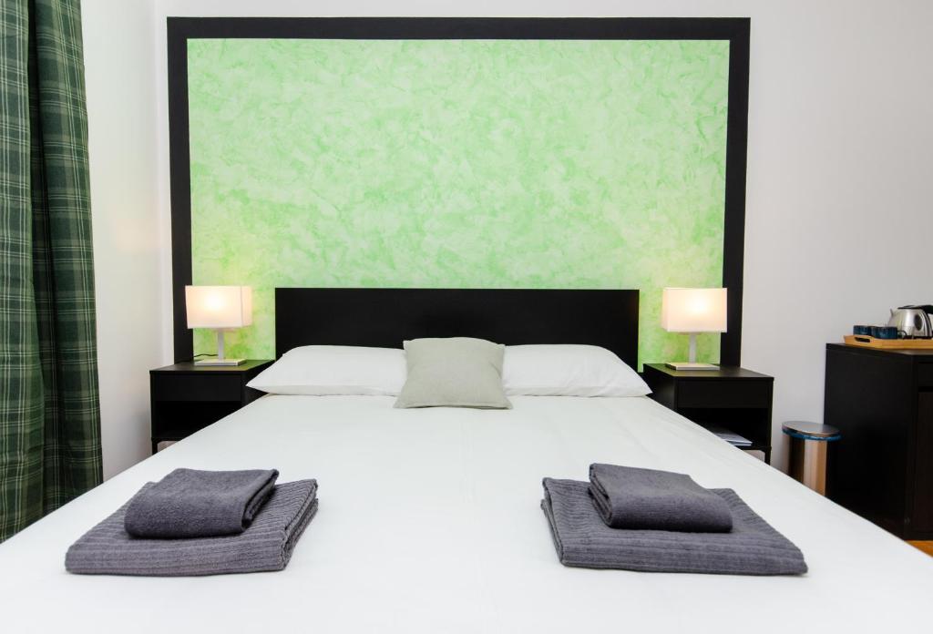 ミラノにあるGreen Roomの白いベッドとタオルが2枚置かれた寝室
