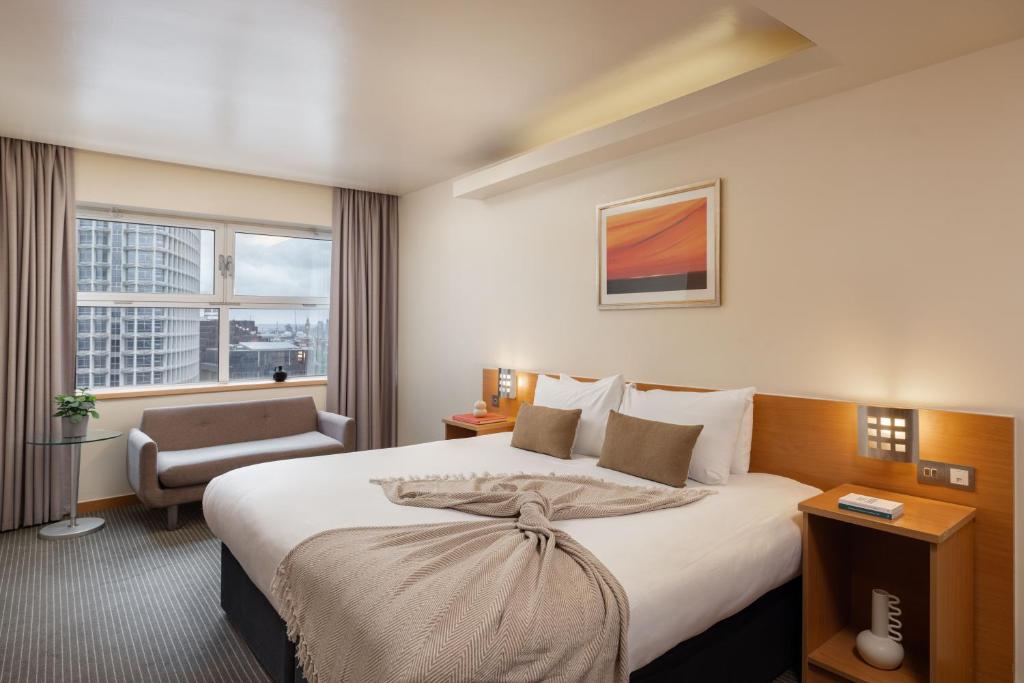 a hotel room with a large bed and a chair at St Giles London – A St Giles Hotel in London