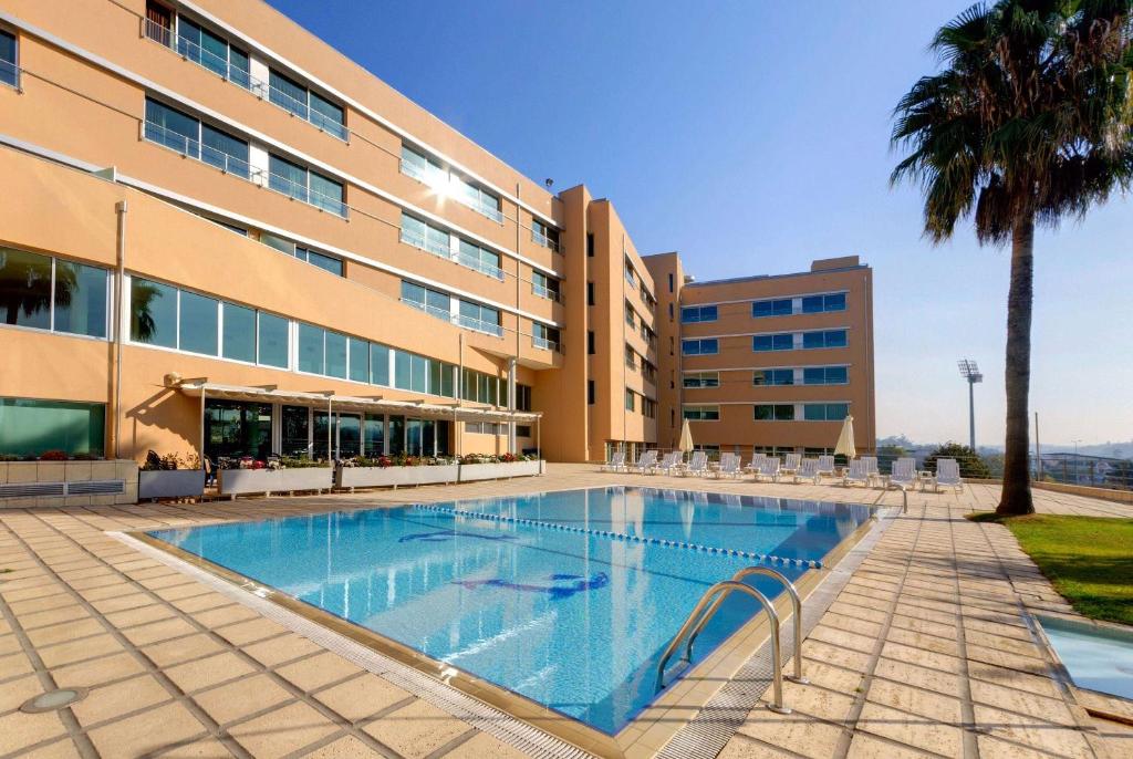 a swimming pool in front of a building at TRYP by Wyndham Porto Expo Hotel in Leça da Palmeira