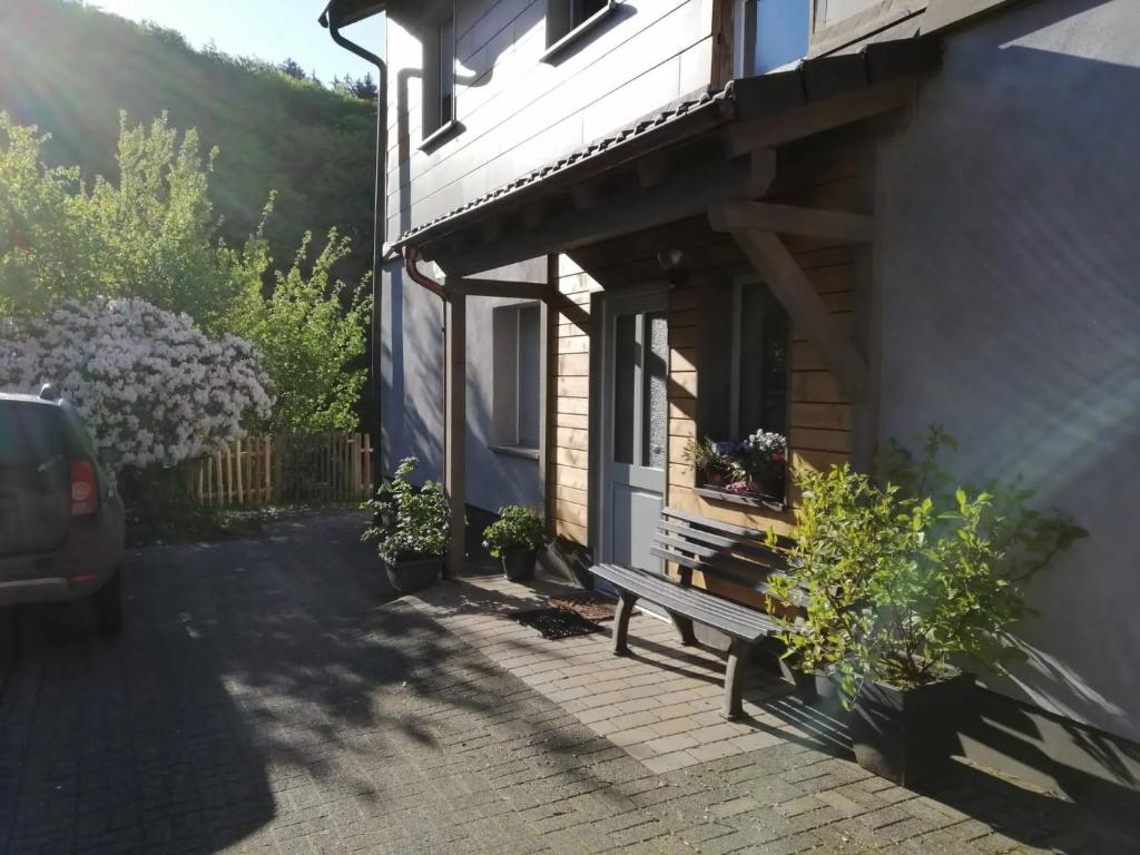 un banc assis à l'extérieur d'une maison avec des fleurs dans l'établissement Ferienwohnung Am Quellental, à Meinerzhagen