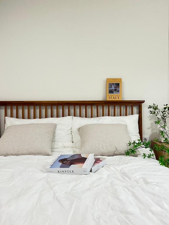 Una cama blanca con un libro encima. en Cream HOUSE, en Busan