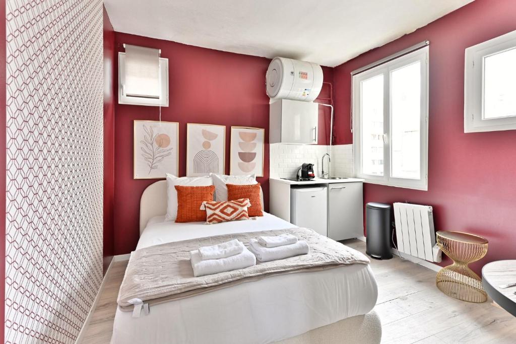 une chambre avec un grand lit blanc dans un mur rouge dans l'établissement Studio Cosy près de Montparnasse, à Paris