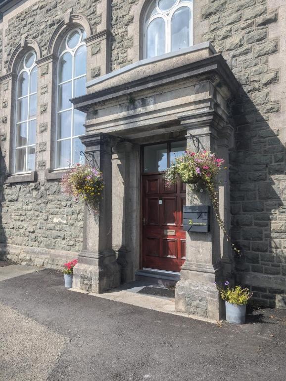 a brick building with a red door with flowers on it at 2 Chapel Nazareth in Penrhyndeudreath