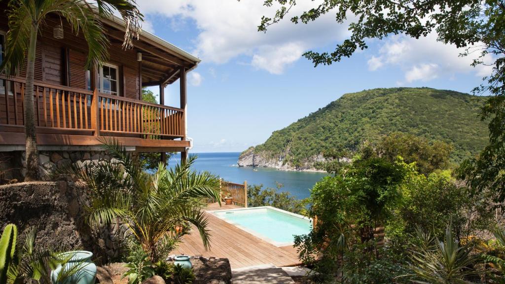 a house with a swimming pool next to the ocean at Palm Bay in Deshaies