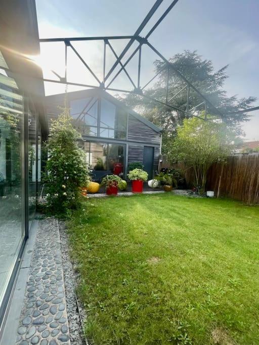 une maison avec une cour verdoyante devant elle dans l'établissement Loft avec Piscine Intérieure et Jardin, à Melun