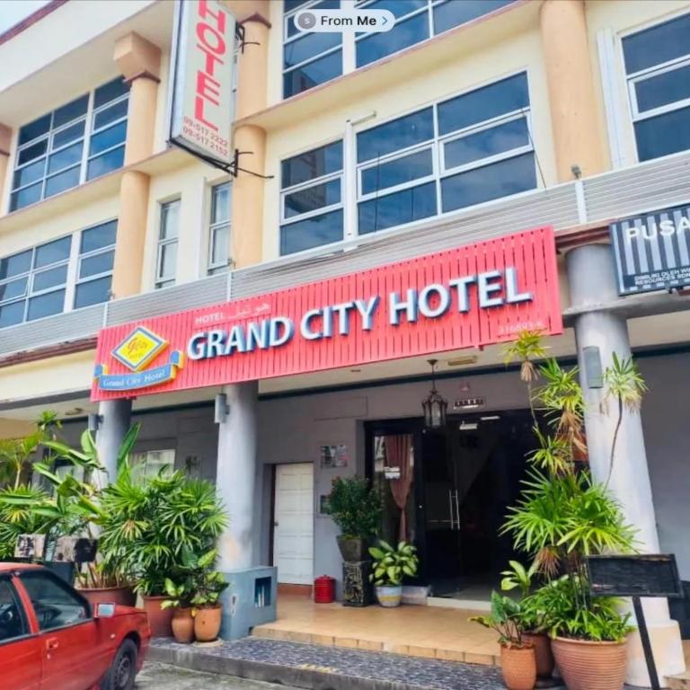 a grand city hotel with a red sign in front of it at Grand City Hotel Kuantan in Kuantan