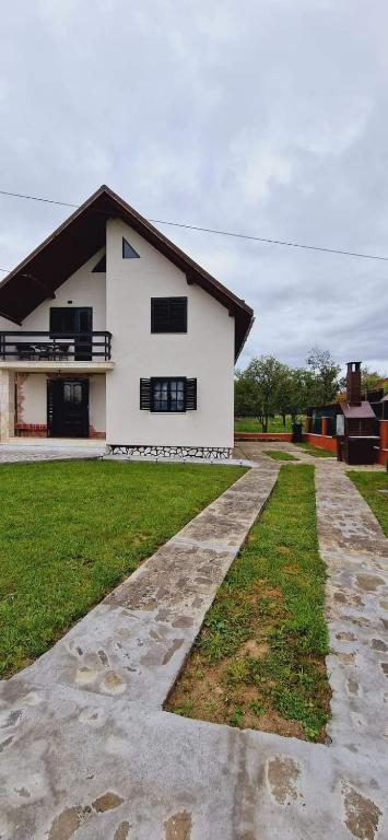 ein weißes Haus mit einem Gehweg davor in der Unterkunft Casa Bilașco in Ocna Şugatag