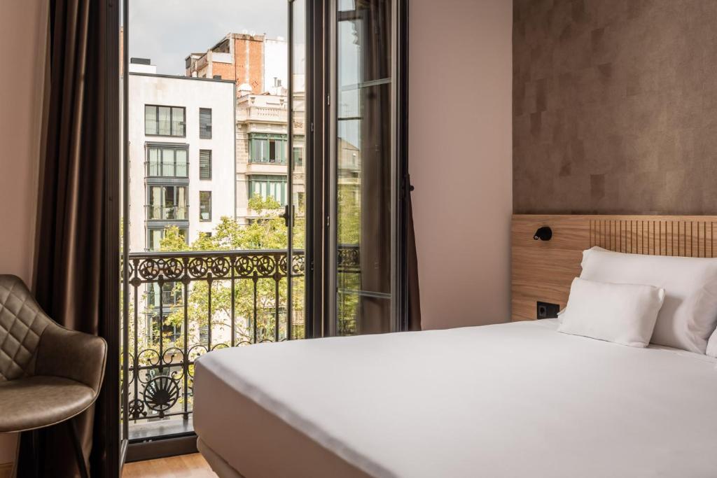 a bedroom with a bed and a large window at Petit Palace Eixample in Barcelona