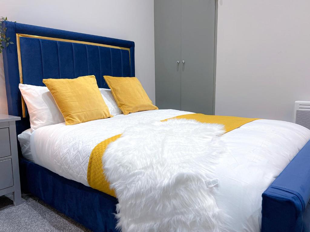 a blue and white bed with yellow pillows on it at Skyline Studios Maida-Vale in London
