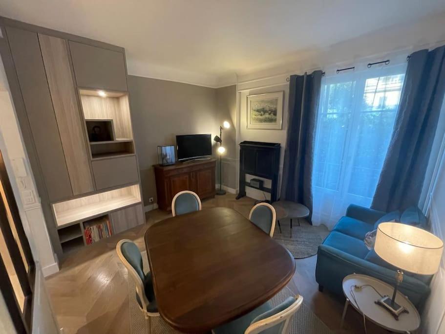 un salon avec une table et un canapé bleu dans l'établissement Appartement Le Joséphine avec jardin privatif, à Rueil-Malmaison